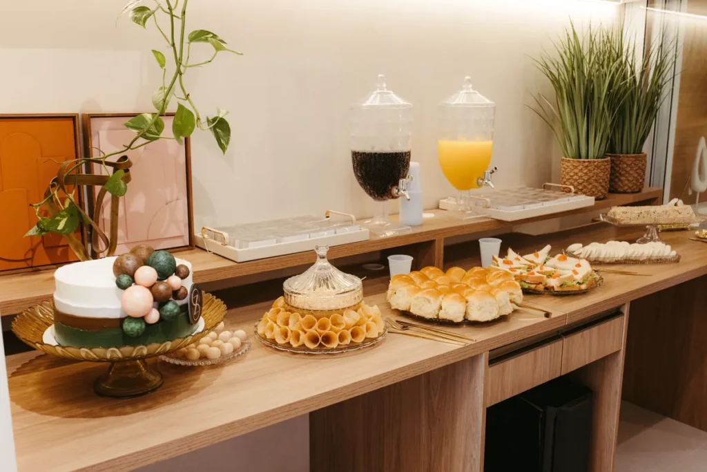 mesa corporativa com salgados, bolo, frutas, café e suco.